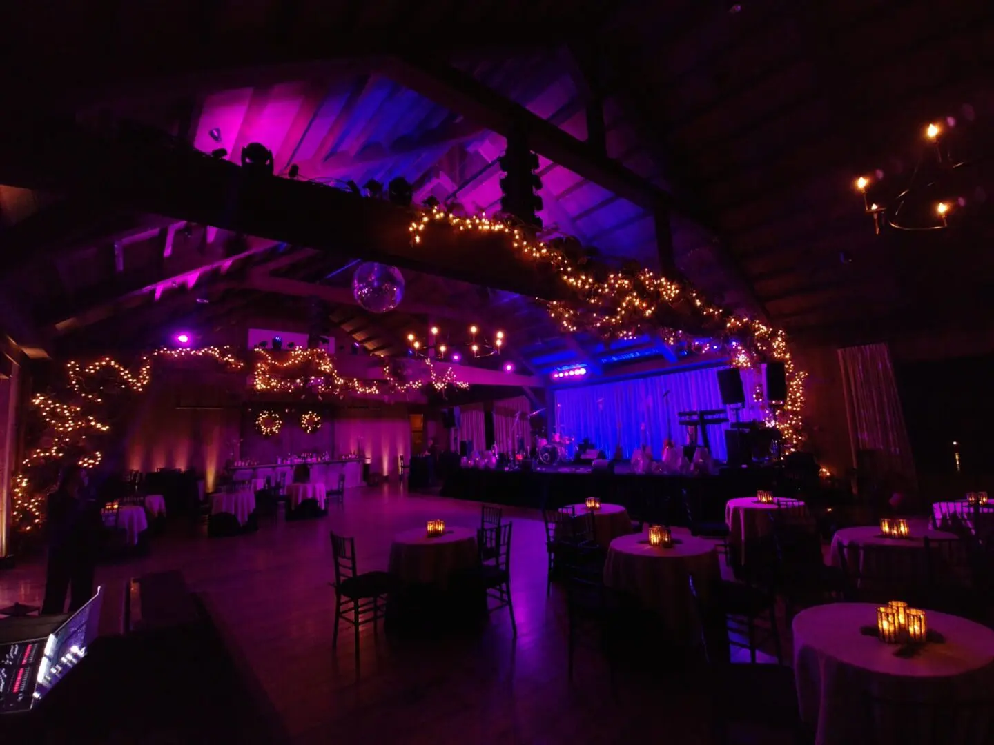 Dimly lit event space with purple and blue lighting and string lights.