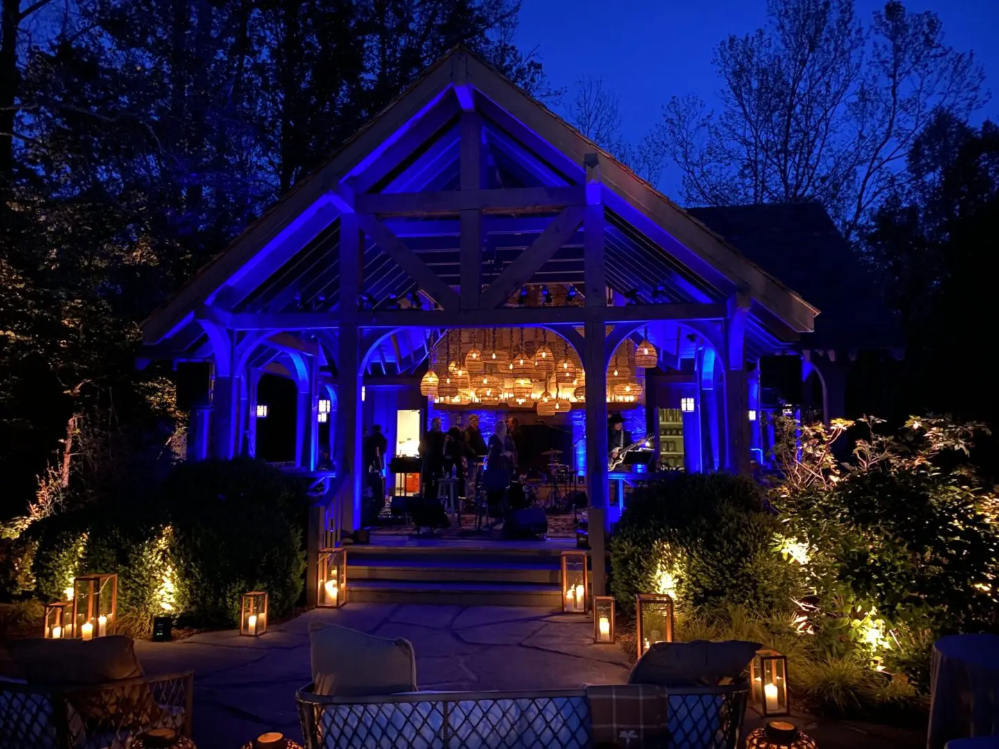 Cozy outdoor pavilion illuminated with warm blue and golden lights at night.