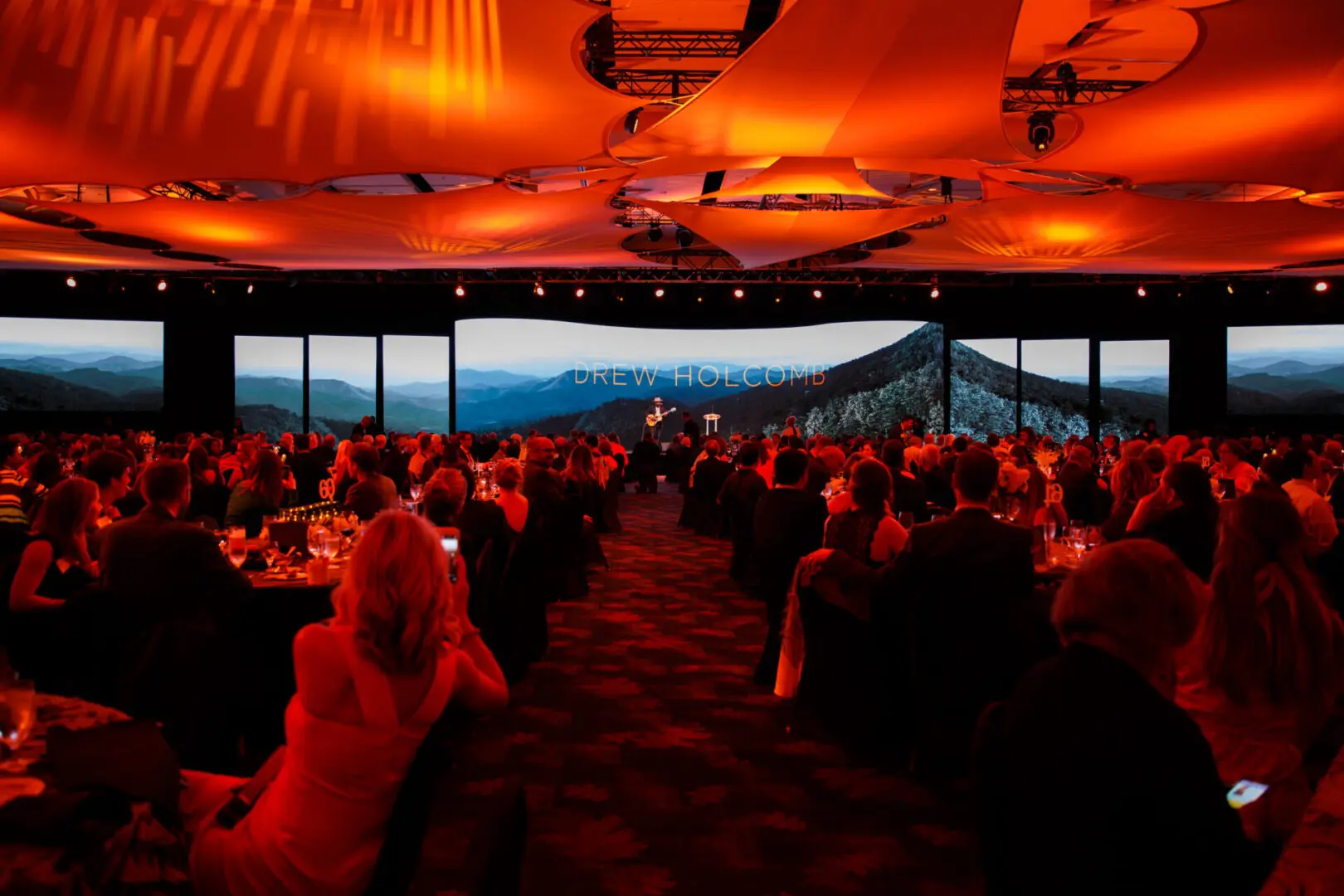 Audience watching a sunset view from an indoor event space.