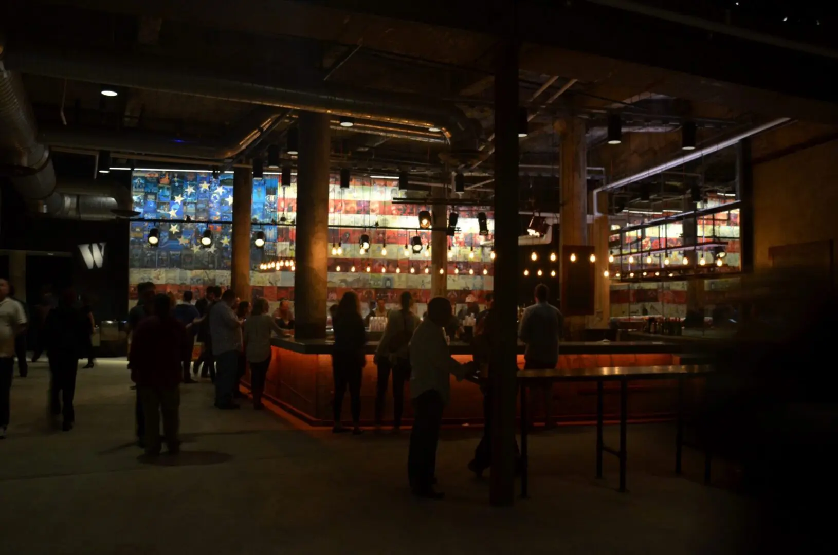 Dimly lit bar with patrons enjoying drinks and conversations.