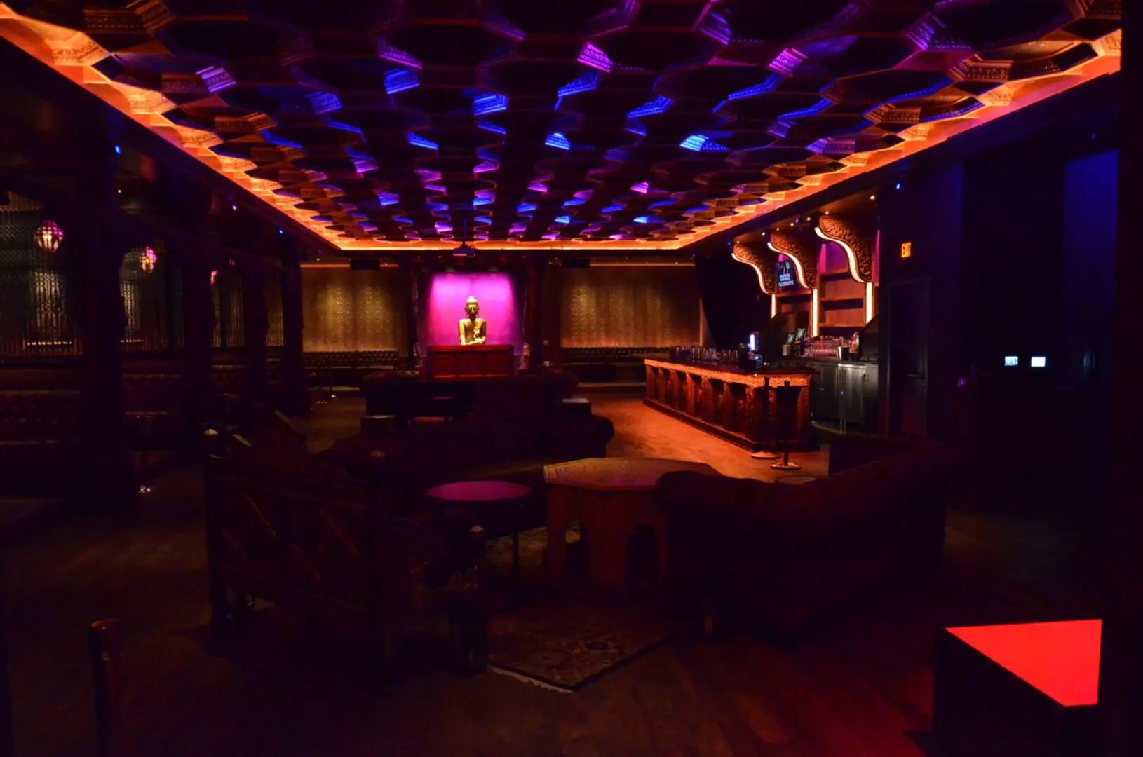 Dimly lit lounge with colorful ceiling lights and cozy seating.