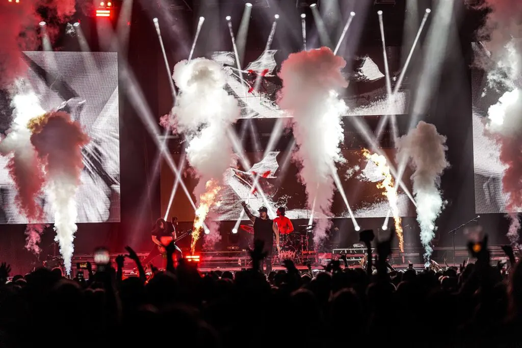 A group of people on stage with smoke coming out of their mouths, featuring HARDY and Bandit Lites.