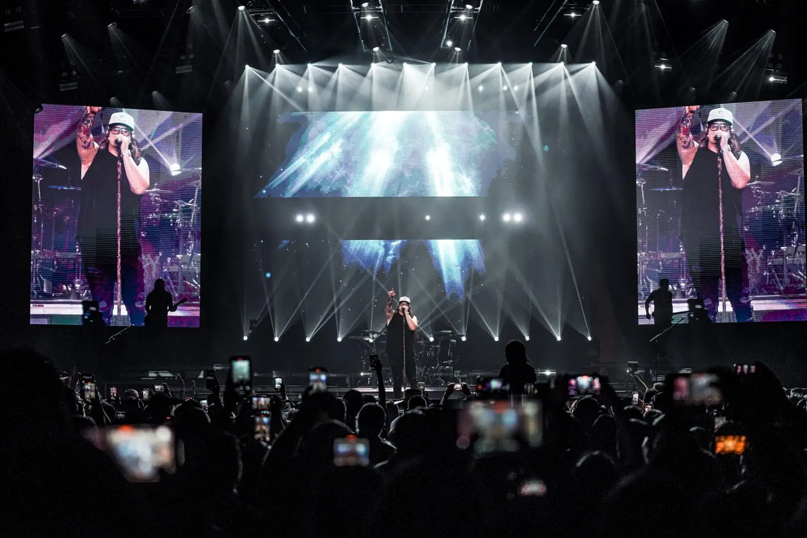 A performer on stage with dramatic lighting and a large crowd.