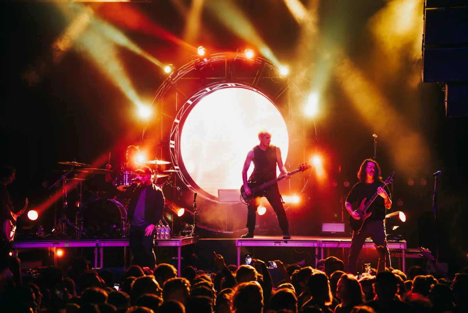 Rock band performing live on stage with vibrant lighting.