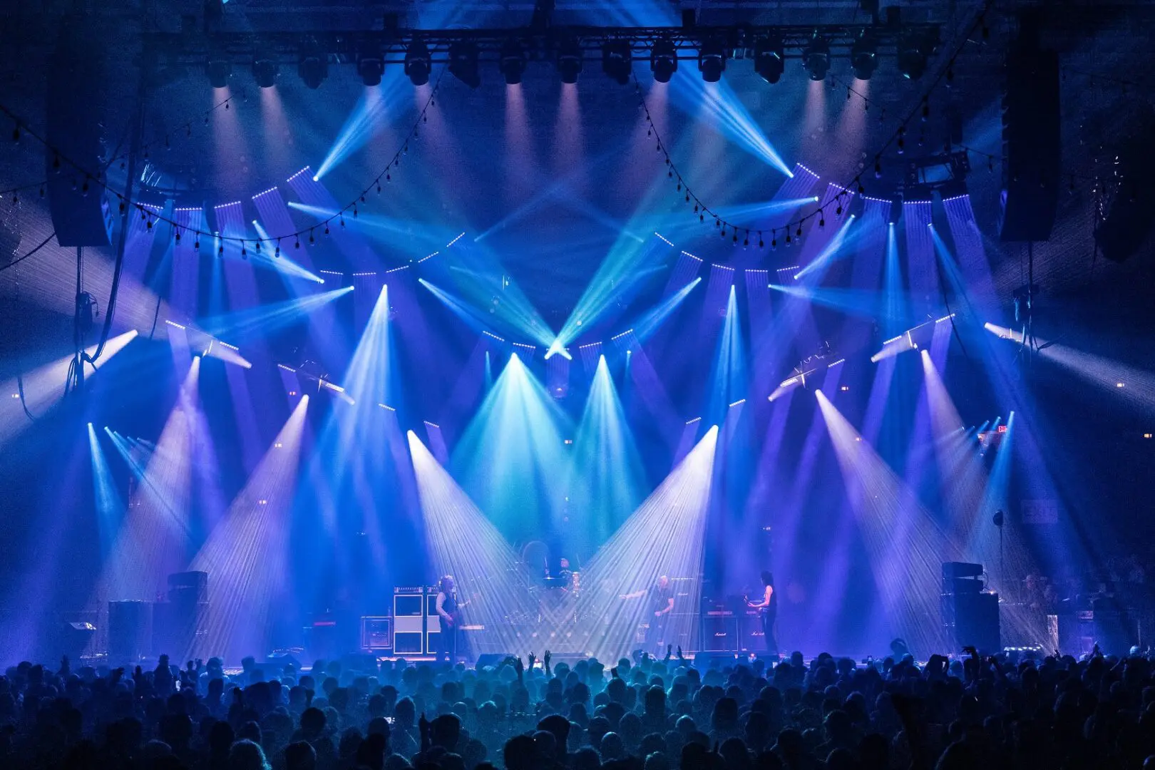 Vibrant blue stage lights illuminate a concert crowd.