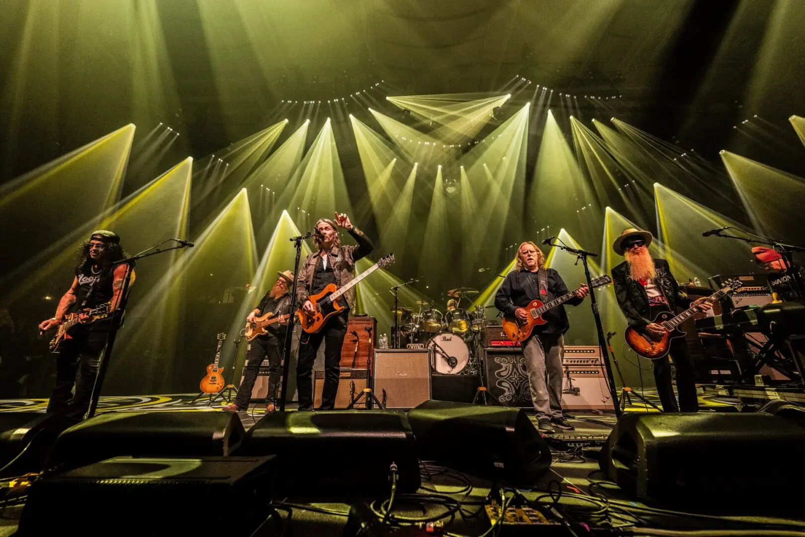 Rock band performing live on stage with dramatic lighting.