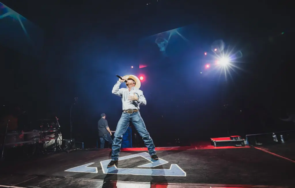 Singer passionately performs on stage with dramatic lighting.
