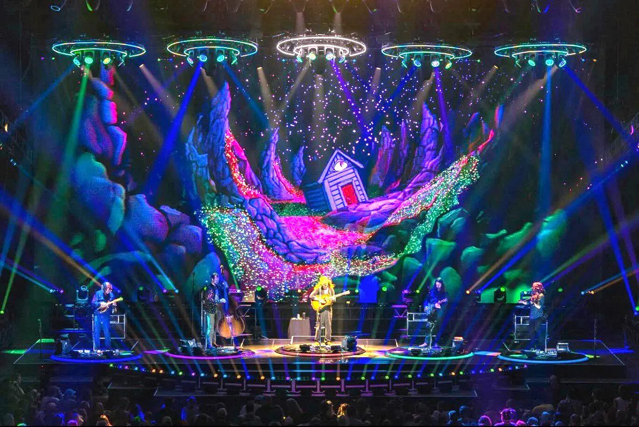 A vibrant stage with colorful lights and a performer playing guitar.