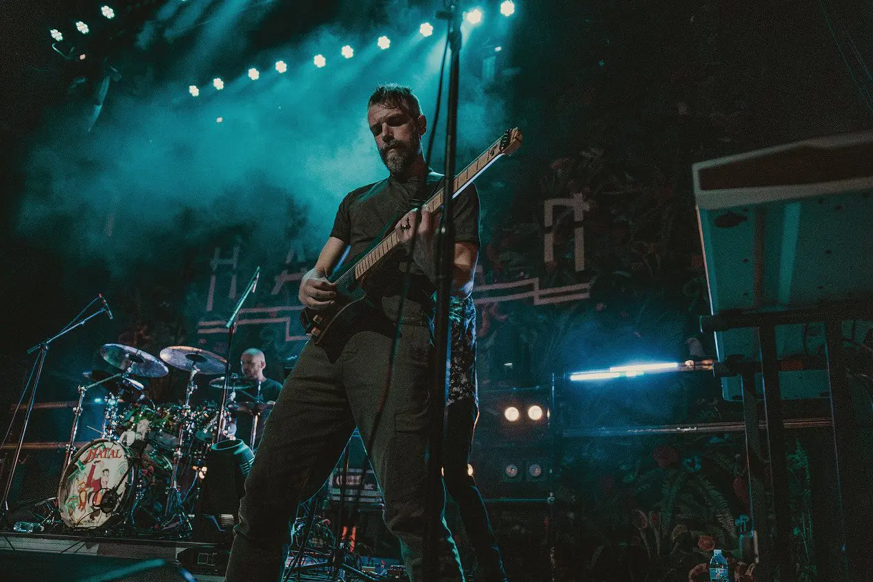 Musician passionately playing guitar on stage with vibrant lighting.