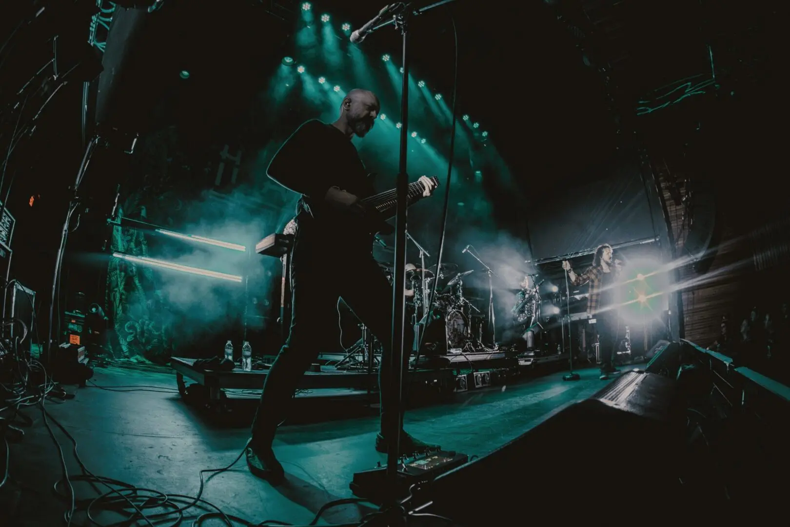 Silhouetted musician performing on a foggy, neon-lit stage.