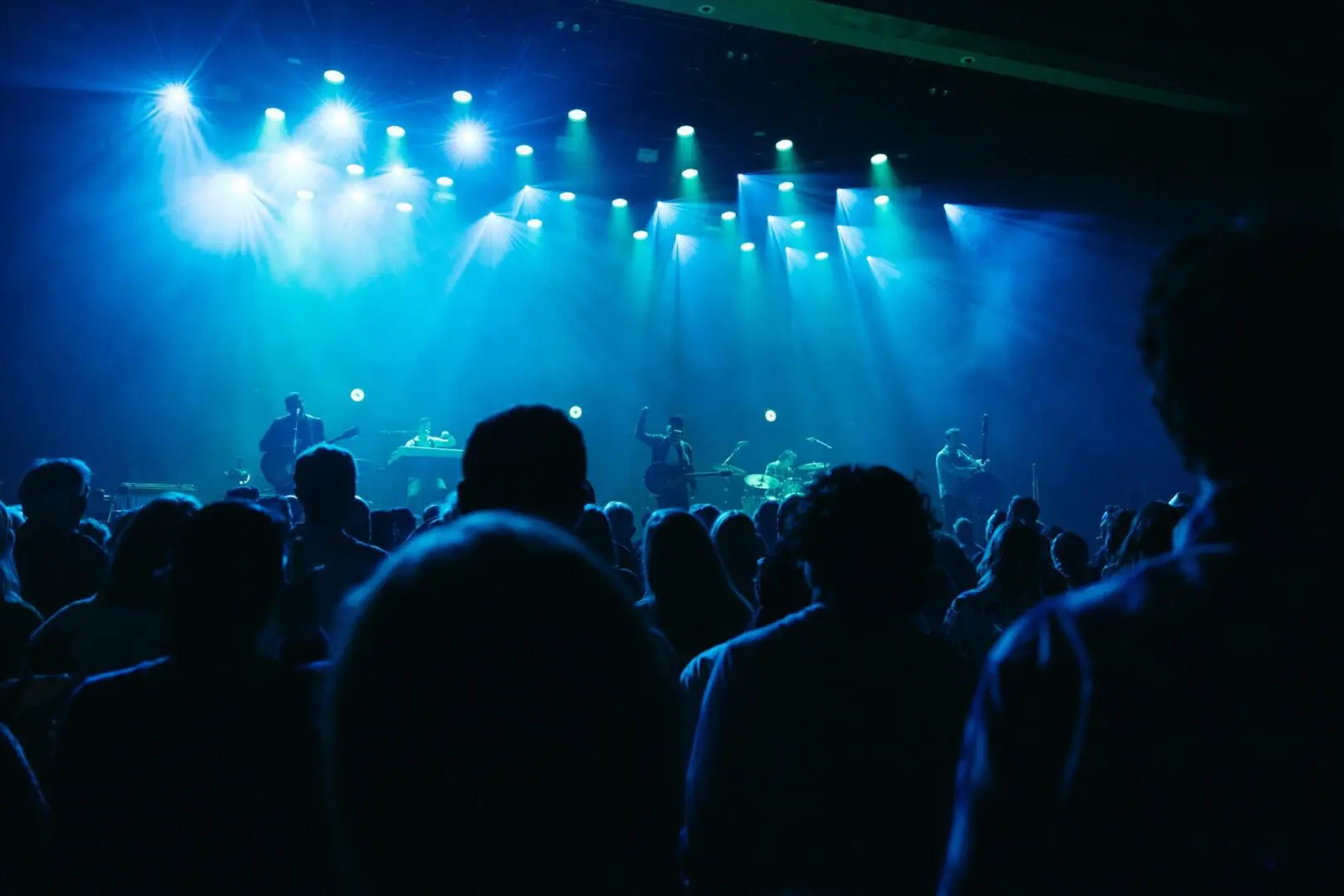 Crowd enjoying a live concert under blue stage lights.