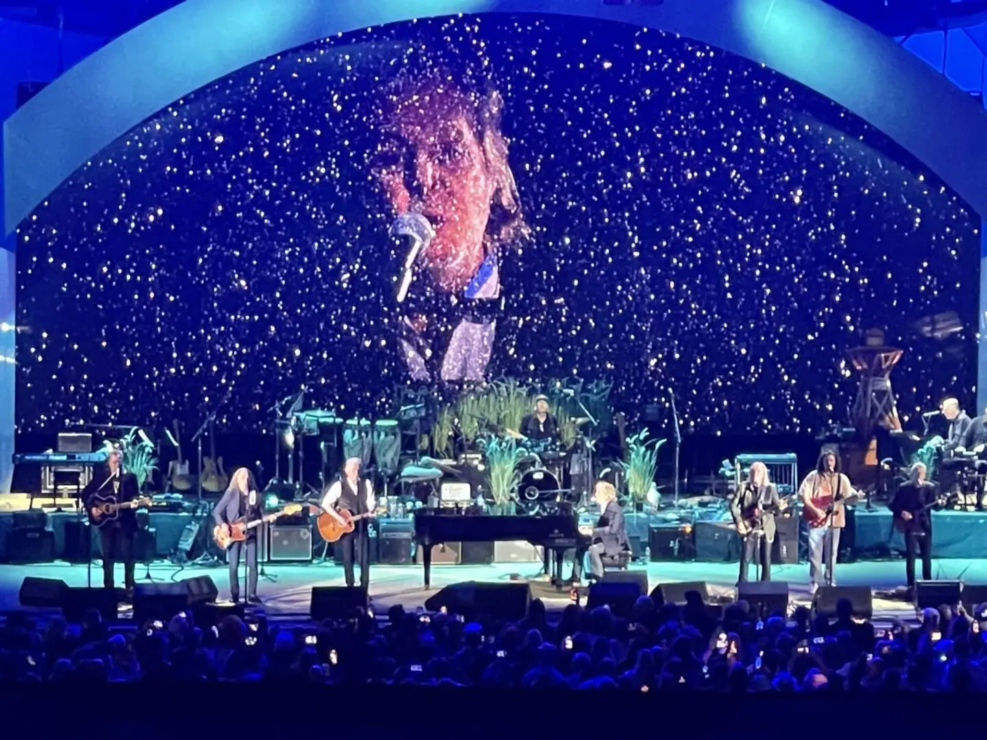 Band performing on stage with vibrant blue lighting and starry background.