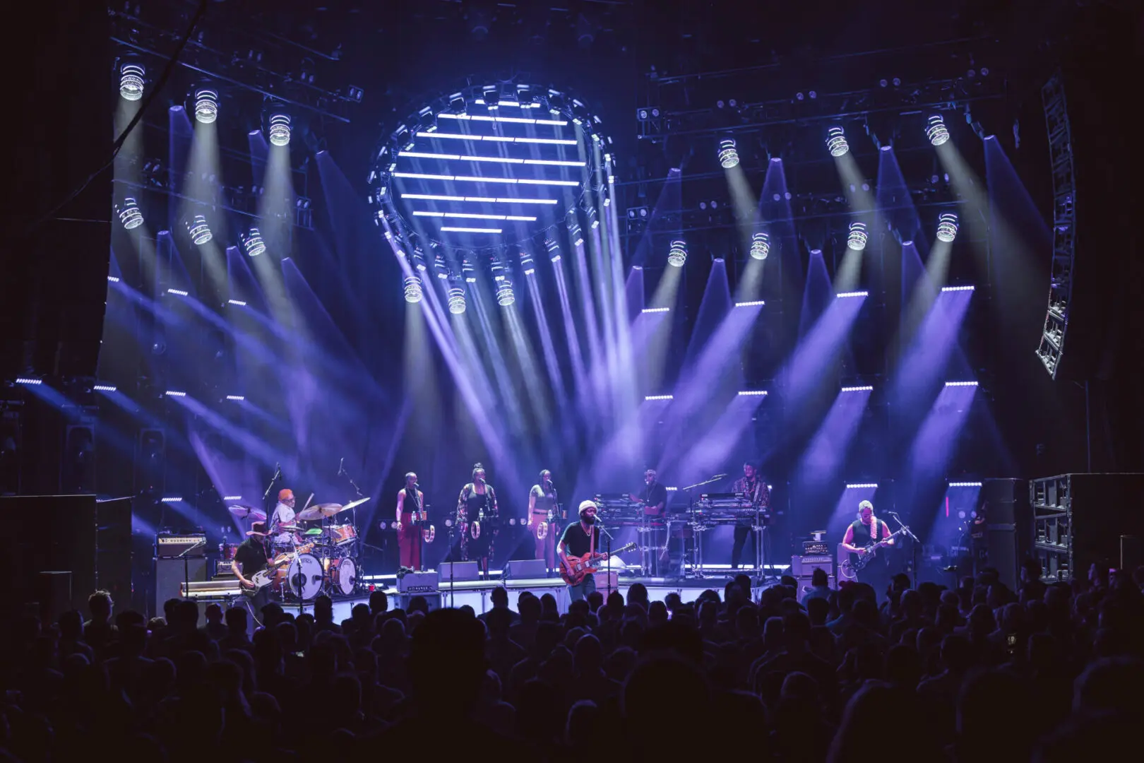 A band performing live on a stage with vibrant blue lighting.