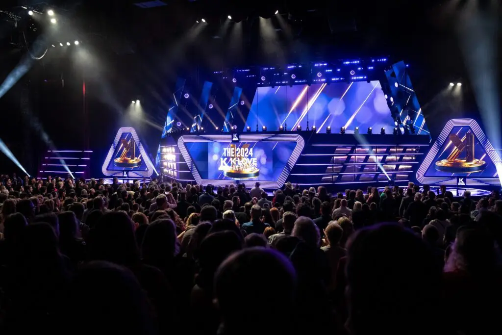 A large crowd watches a brightly lit stage at a gaming event.