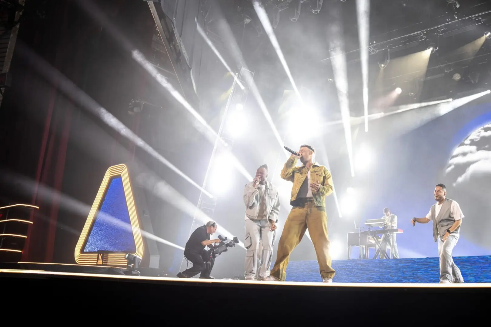 Performers on stage with bright lights and dynamic poses.