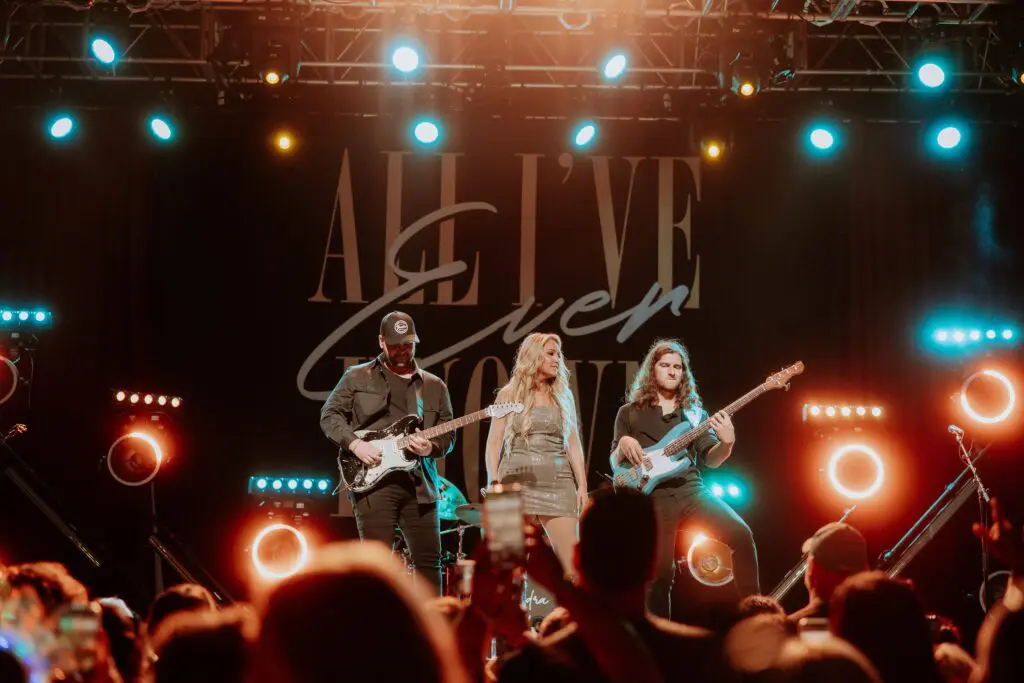 A live band performs energetically on stage with vibrant lighting.