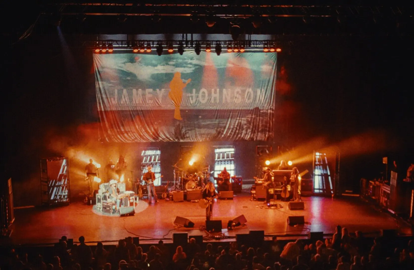 Live concert with band playing under vibrant stage lights.