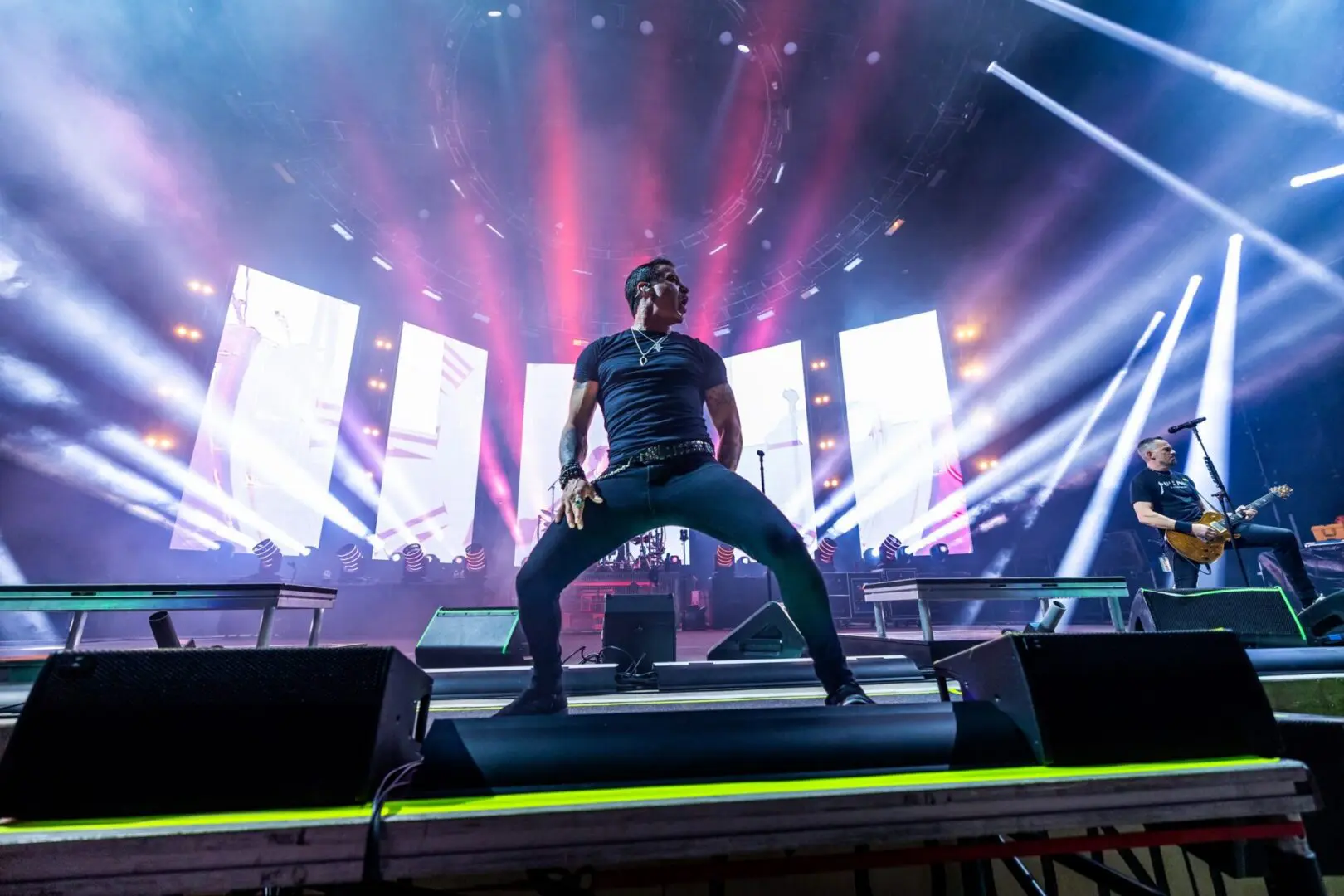 Energetic singer performing on stage with vibrant lights.