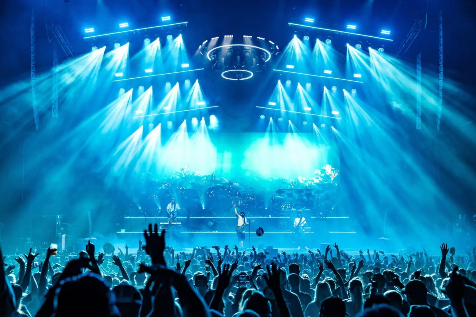 A live concert with bright blue stage lights and a cheering crowd.