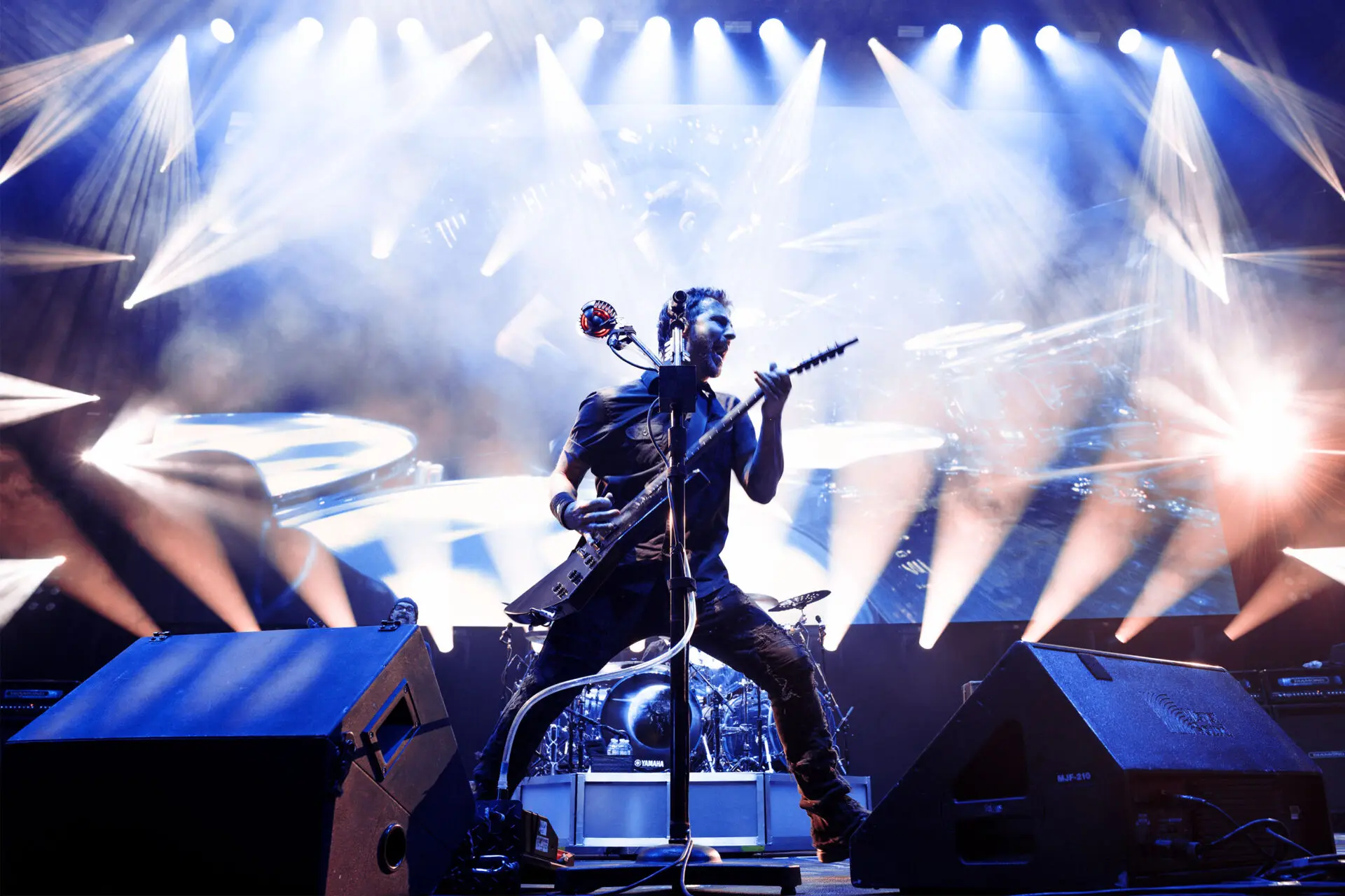 Rock musician passionately playing guitar on stage under bright spotlights.