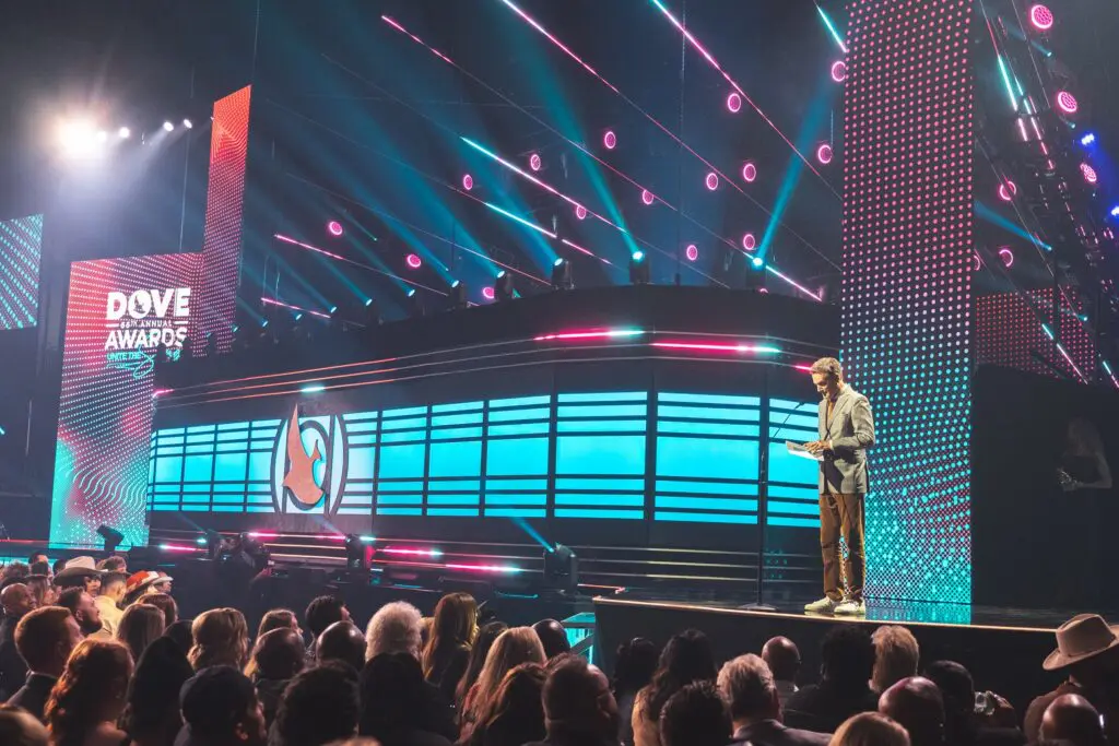 A performer on stage with vibrant lighting and a large audience.