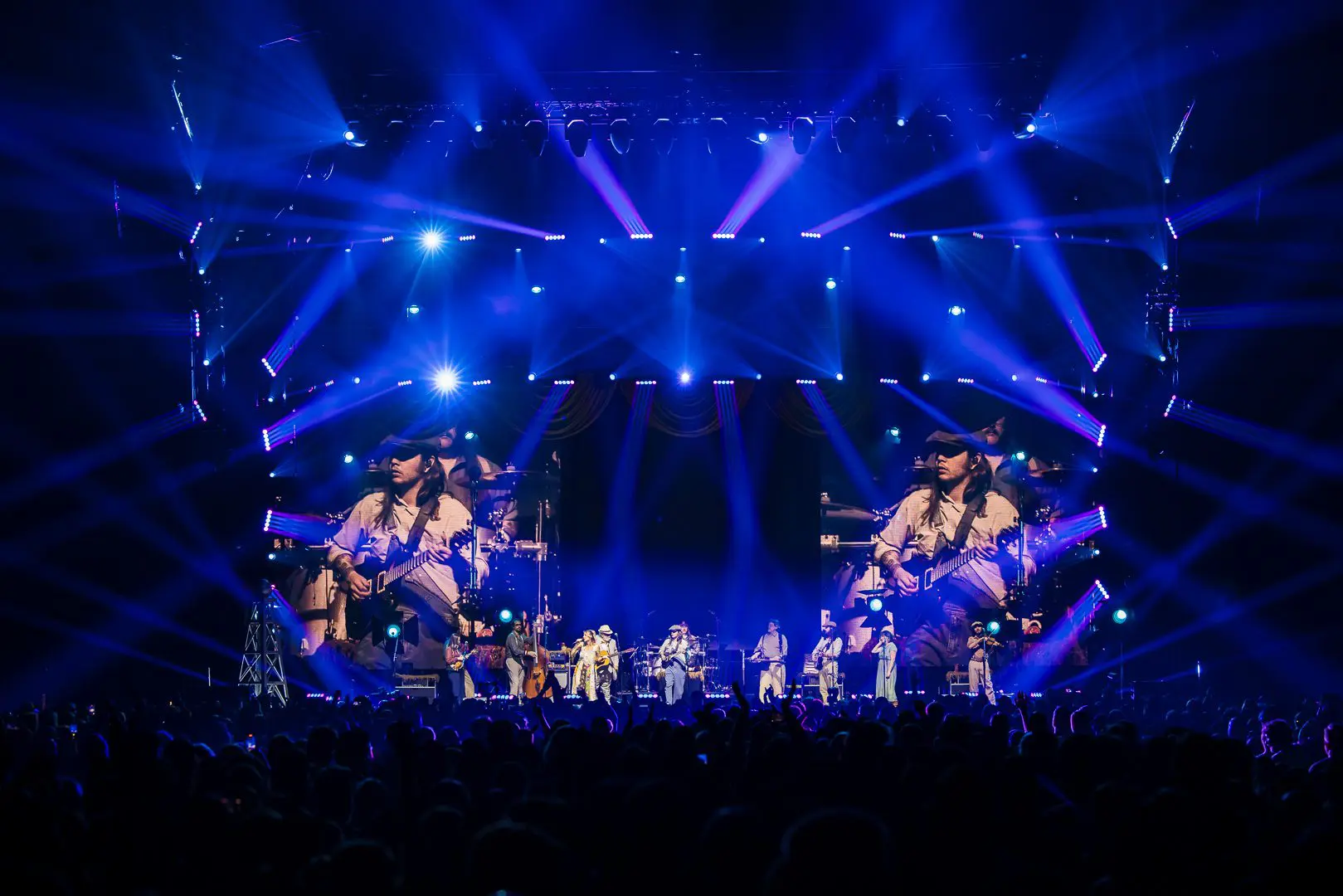 A dynamic dance performance with bright blue lights and mirrored visuals on stage.