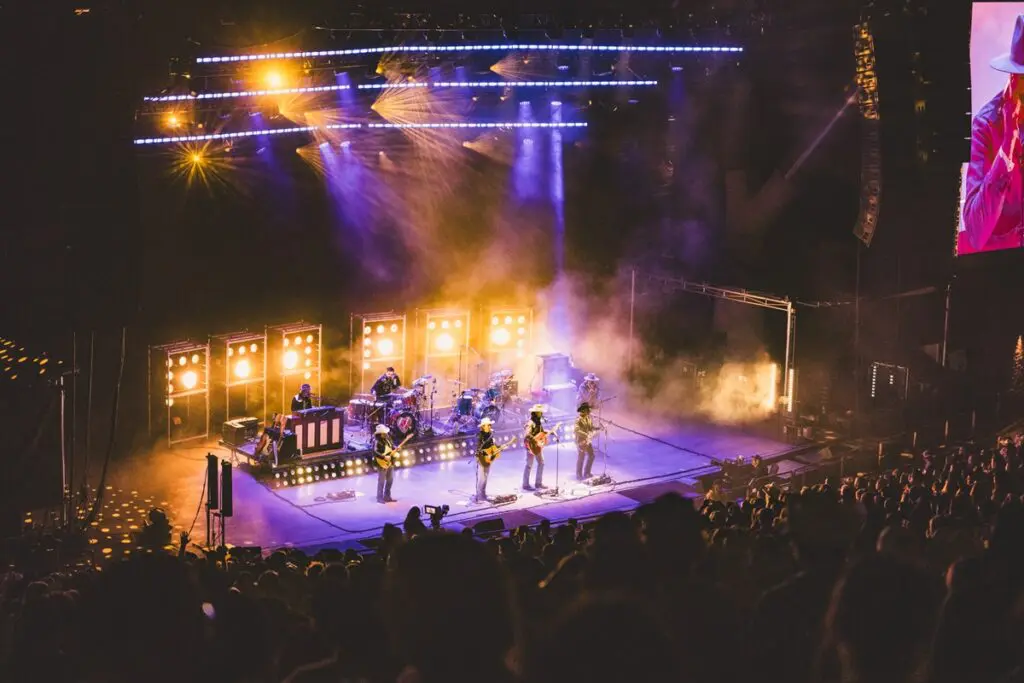 A live band performs on a brightly lit stage with an enthusiastic crowd.