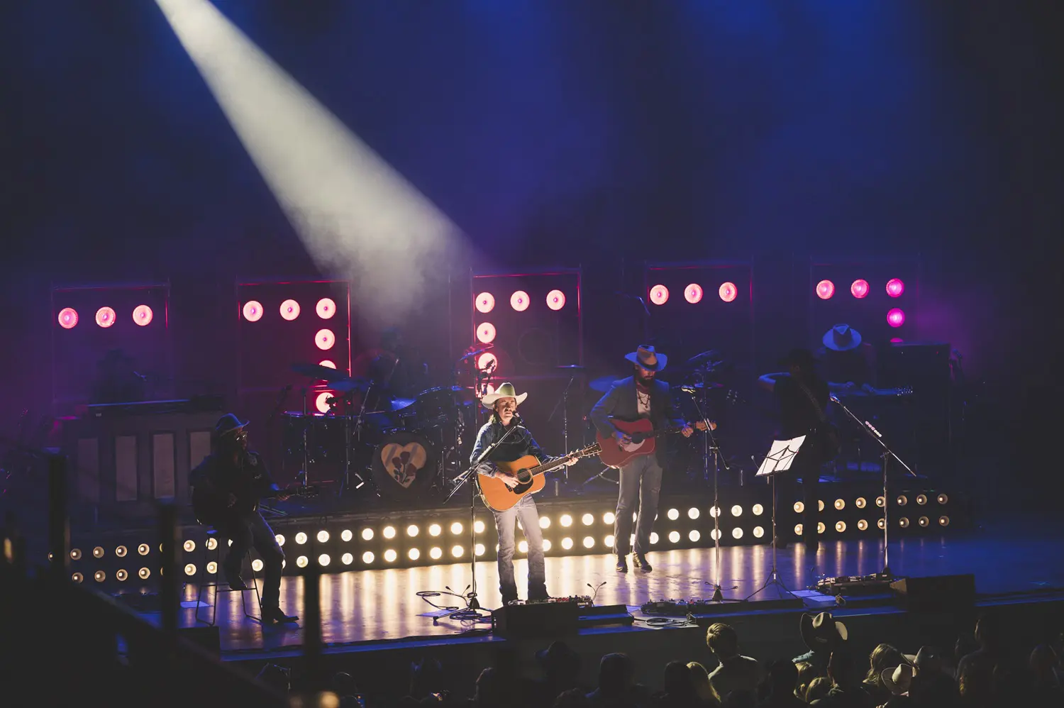 A band performing on stage with colorful lights and smoke effects.