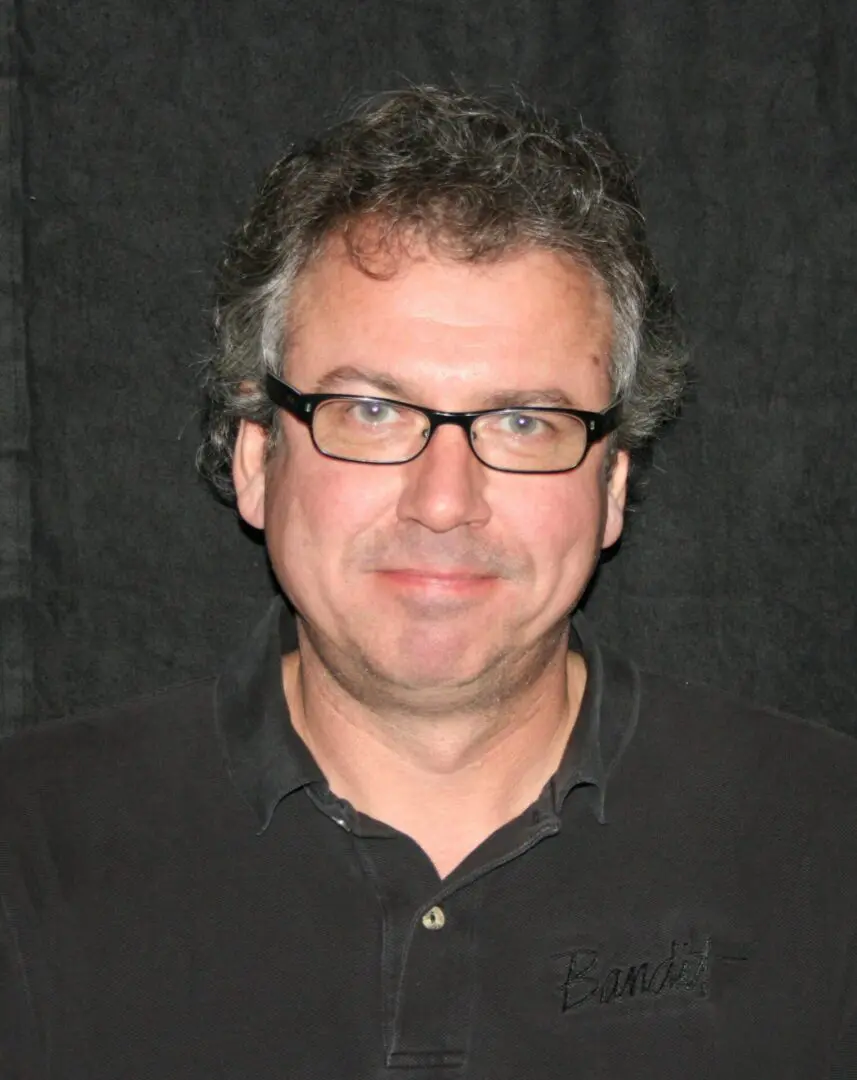 Middle-aged man with glasses and a black shirt.