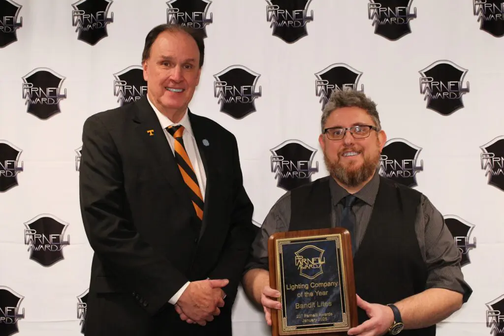 Two men at an award ceremony, one holding a plaque.