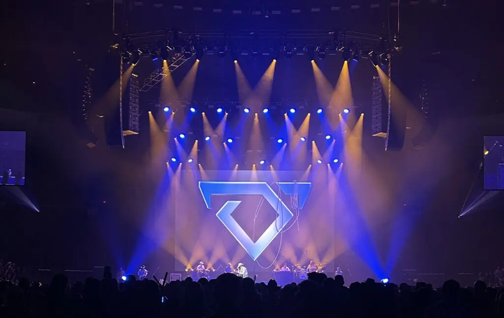Concert stage with vibrant blue and orange lights and a geometric design.