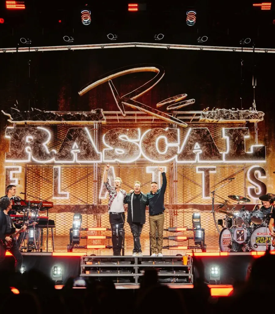 Performers on stage at Rascal Flatts concert with vibrant lighting.