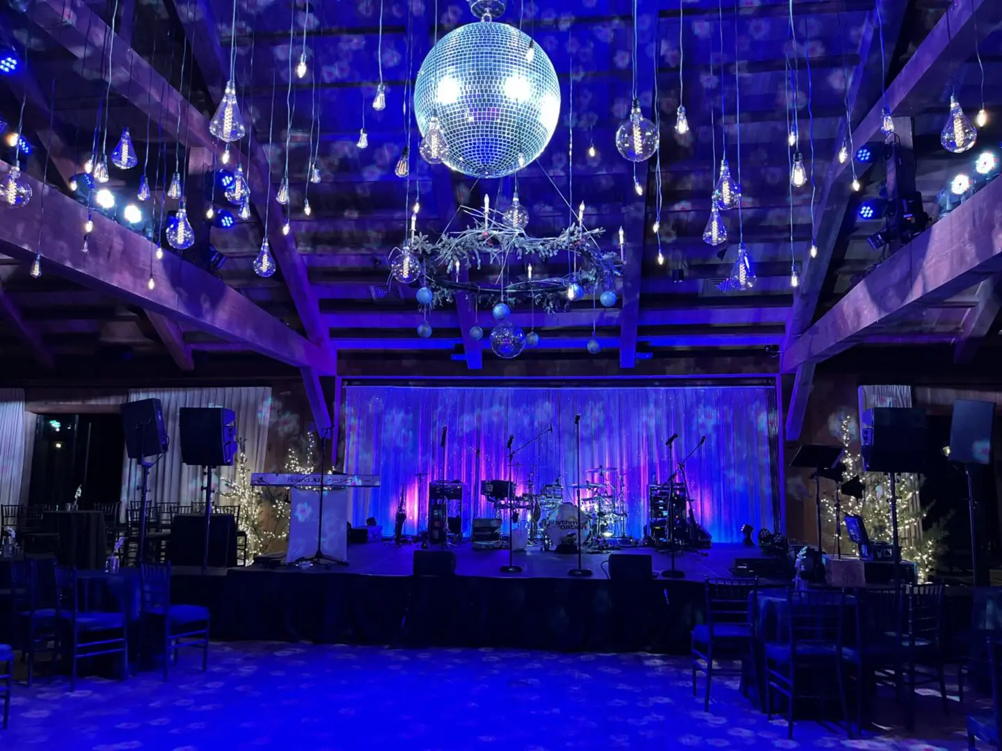 A dimly lit event space with blue and purple lighting and a disco ball.