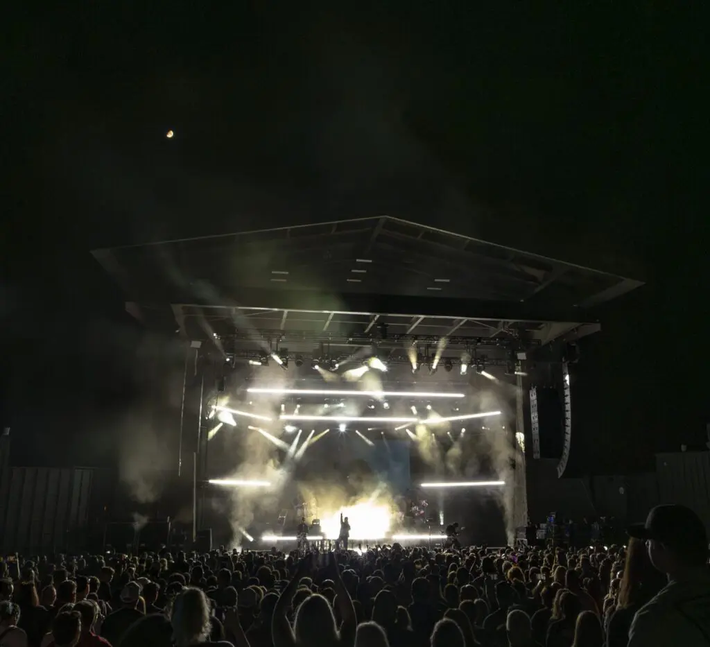 Crowd enjoying a night concert with bright stage lights.