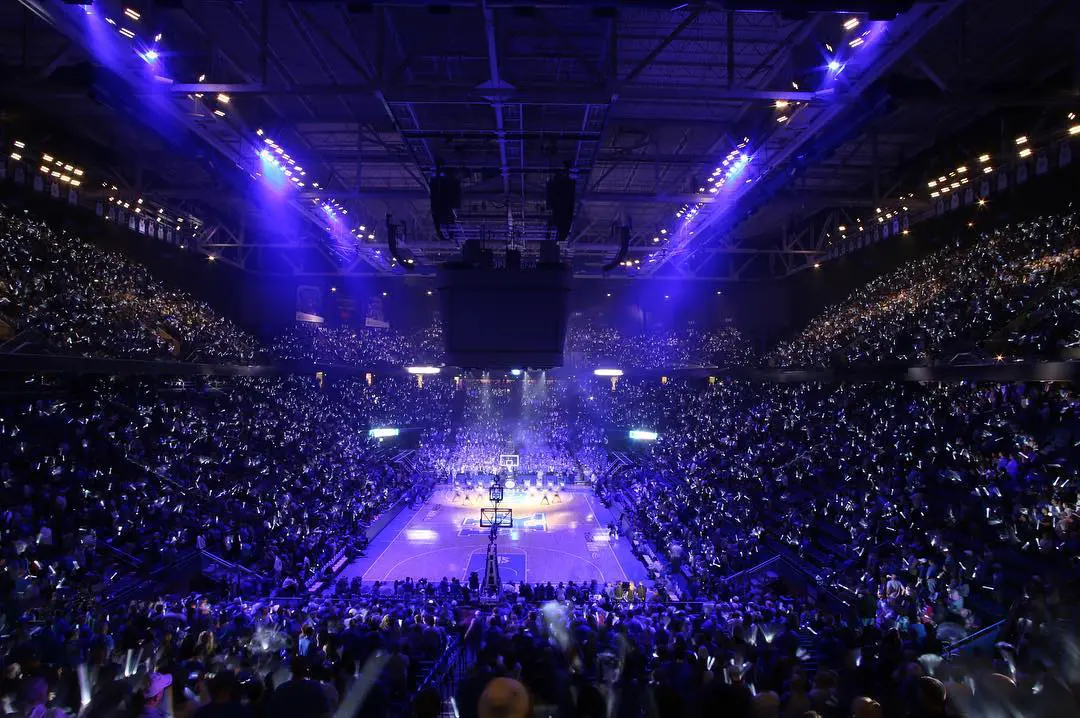 A packed arena with purple lighting during a live event.