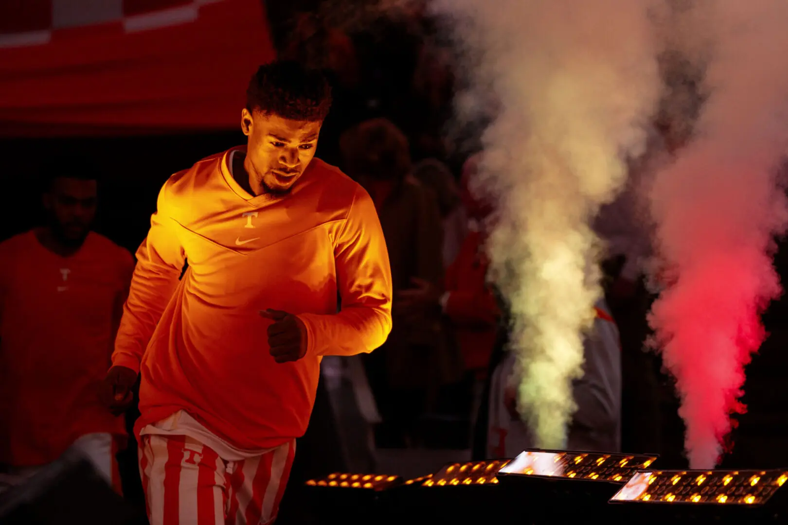 Man lighting candles with smoke rising in a dimly lit setting.