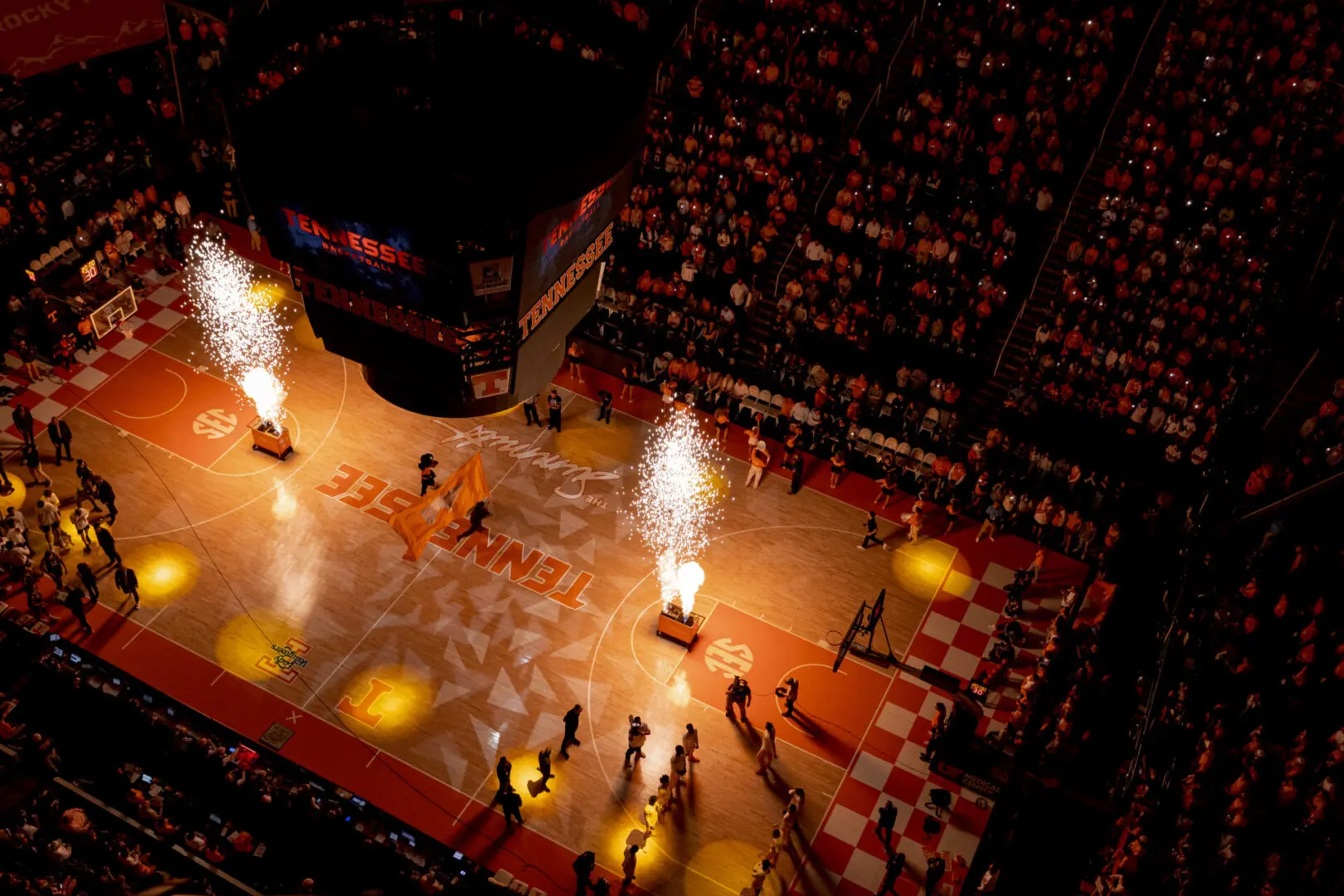 Ice hockey players enter the rink amid fiery pyrotechnics and a cheering crowd.
