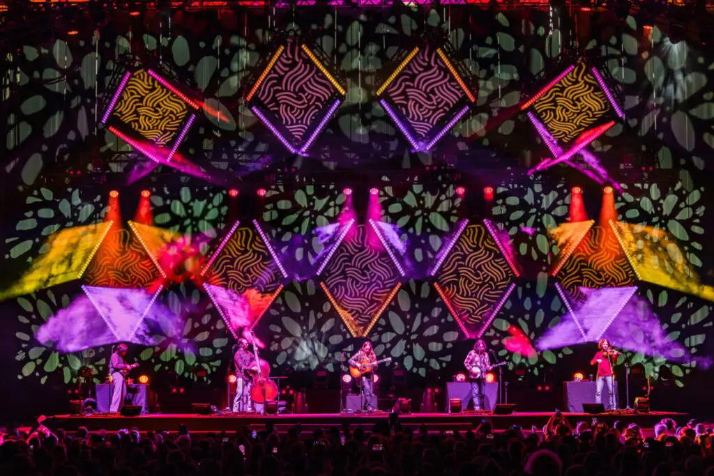 Colorful stage with vibrant geometric lights and performers.