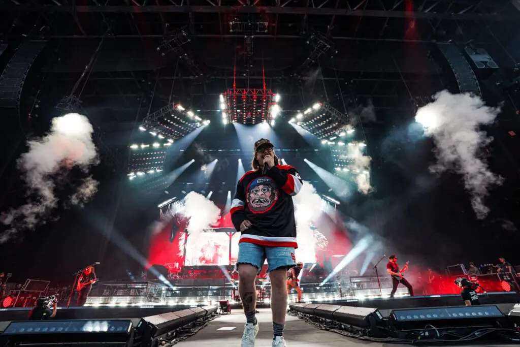 A performer on stage with dynamic lighting and smoke effects at a concert.