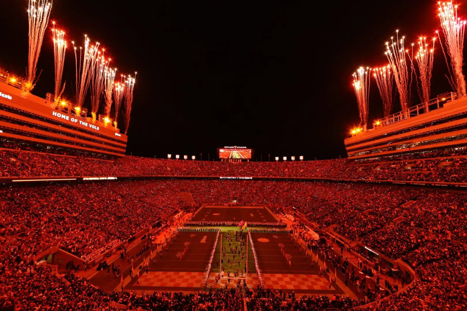 A football stadium illuminated with vibrant red lights during a night game.