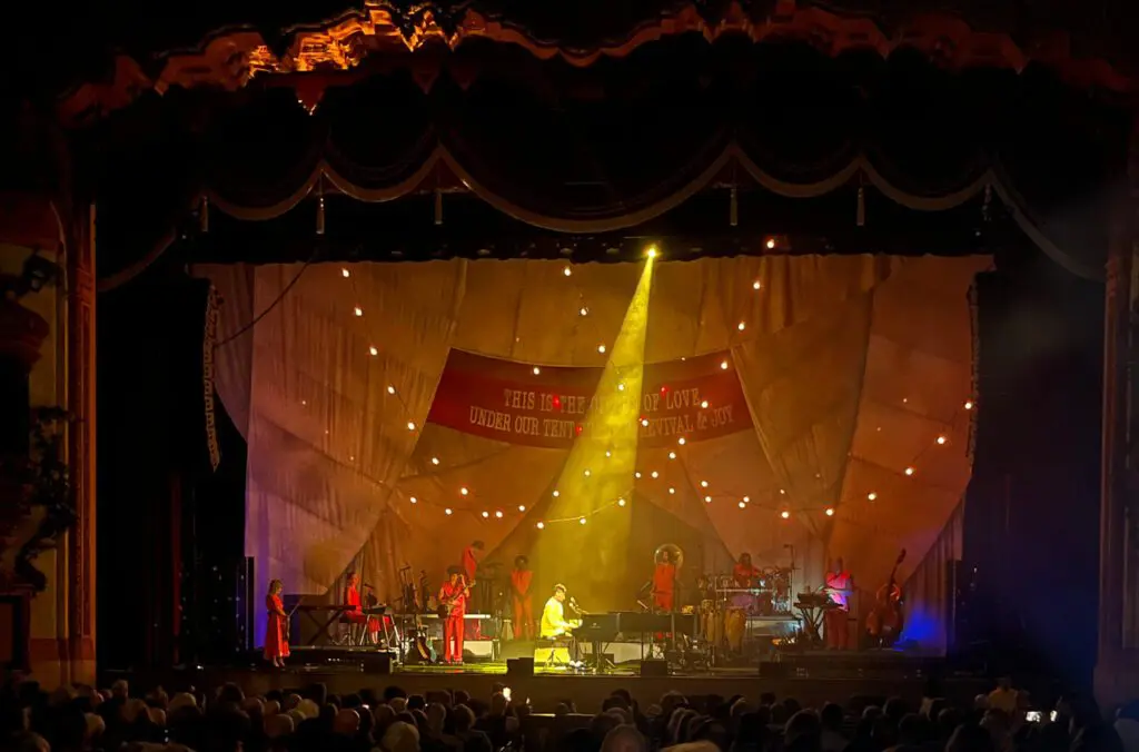 Musician performing under a spotlight on a decorated stage at a live event.