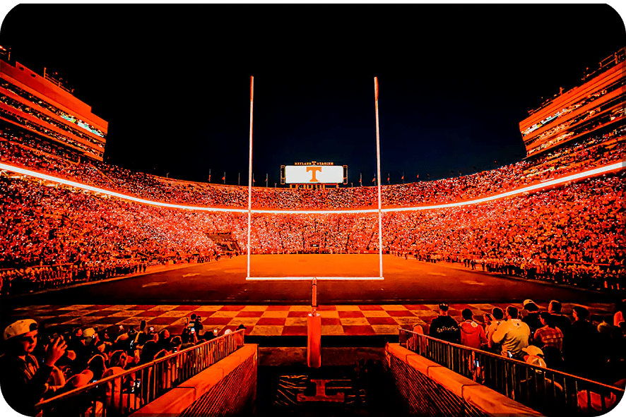 A brightly lit football stadium at night with an empty field.