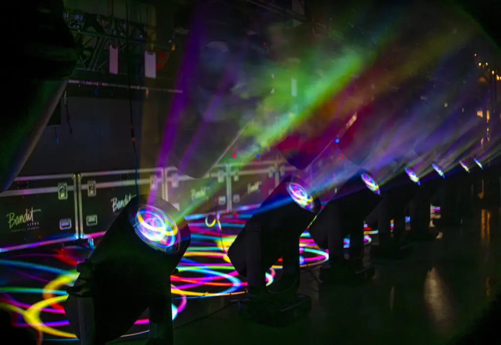 Colorful stage lights creating vibrant beams in a dark room.