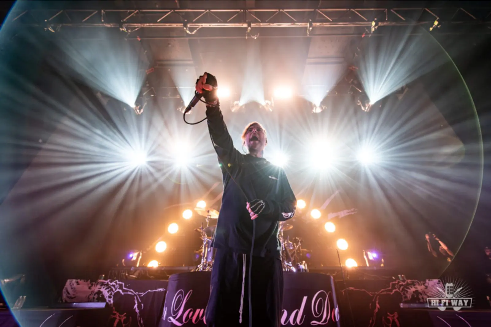 Vocalist passionately performing on stage with dramatic lighting.