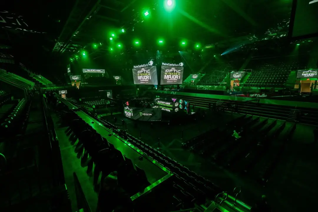 A dimly lit arena with green lights and large screens above the stage.