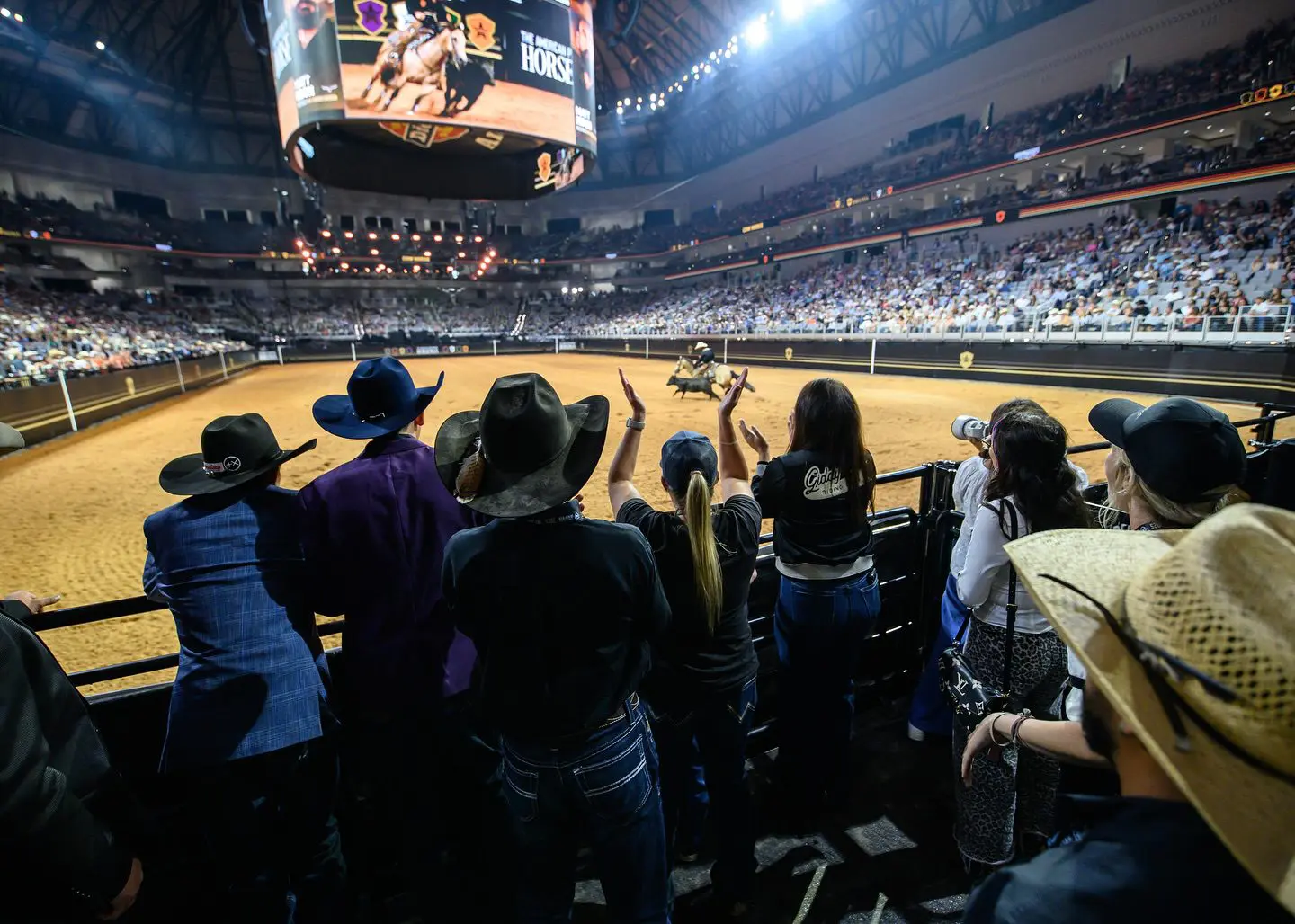 Fans watch a basketball game in a packed indoor arena.