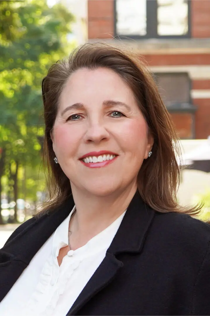 Professional woman smiling outdoors in business attire.