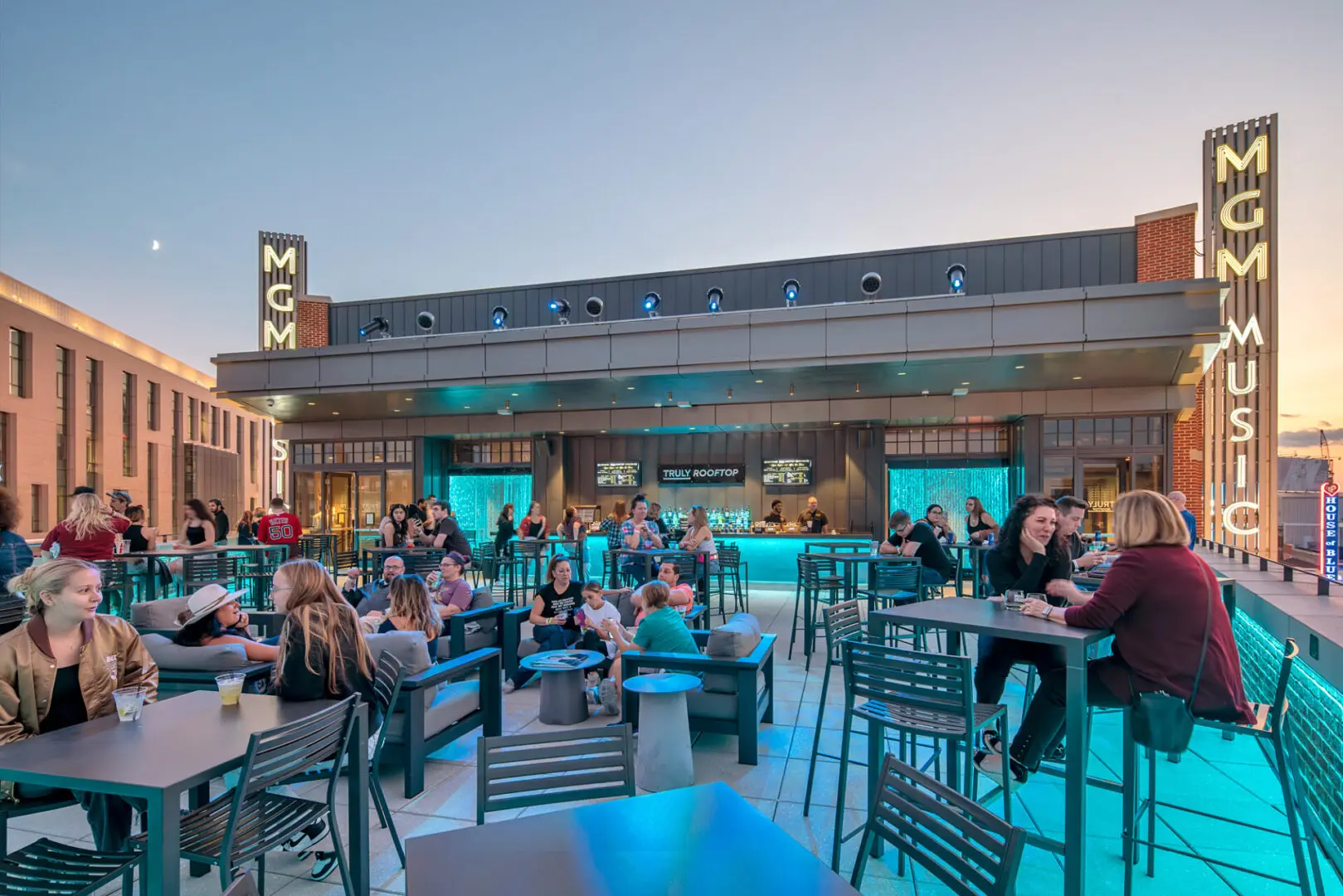 People enjoying a lively evening at an outdoor bar with MGM signage.