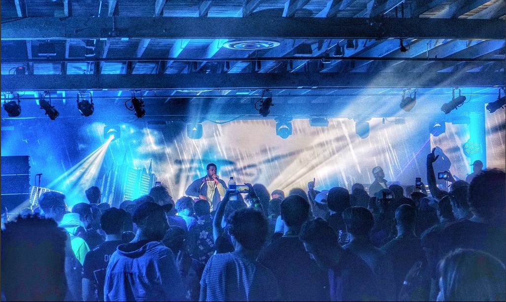 Crowded concert with blue lighting and energetic crowd.