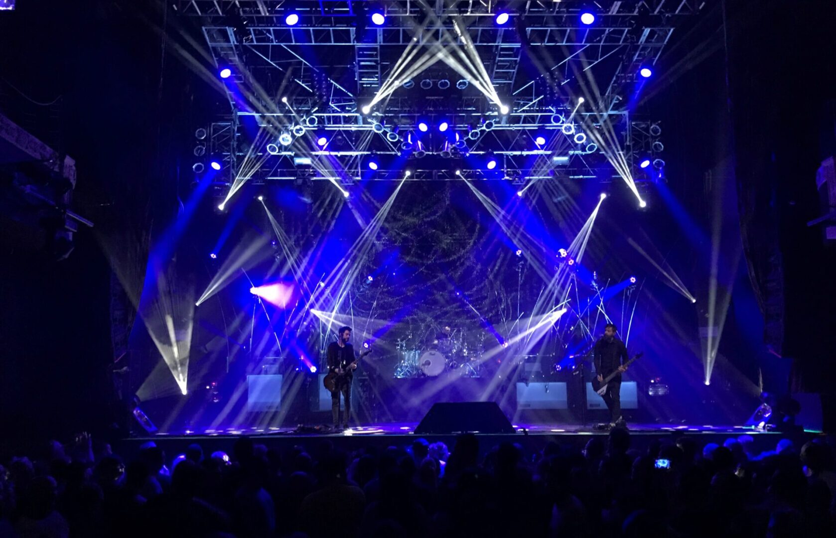 A vibrant concert stage with blue lighting and laser effects.